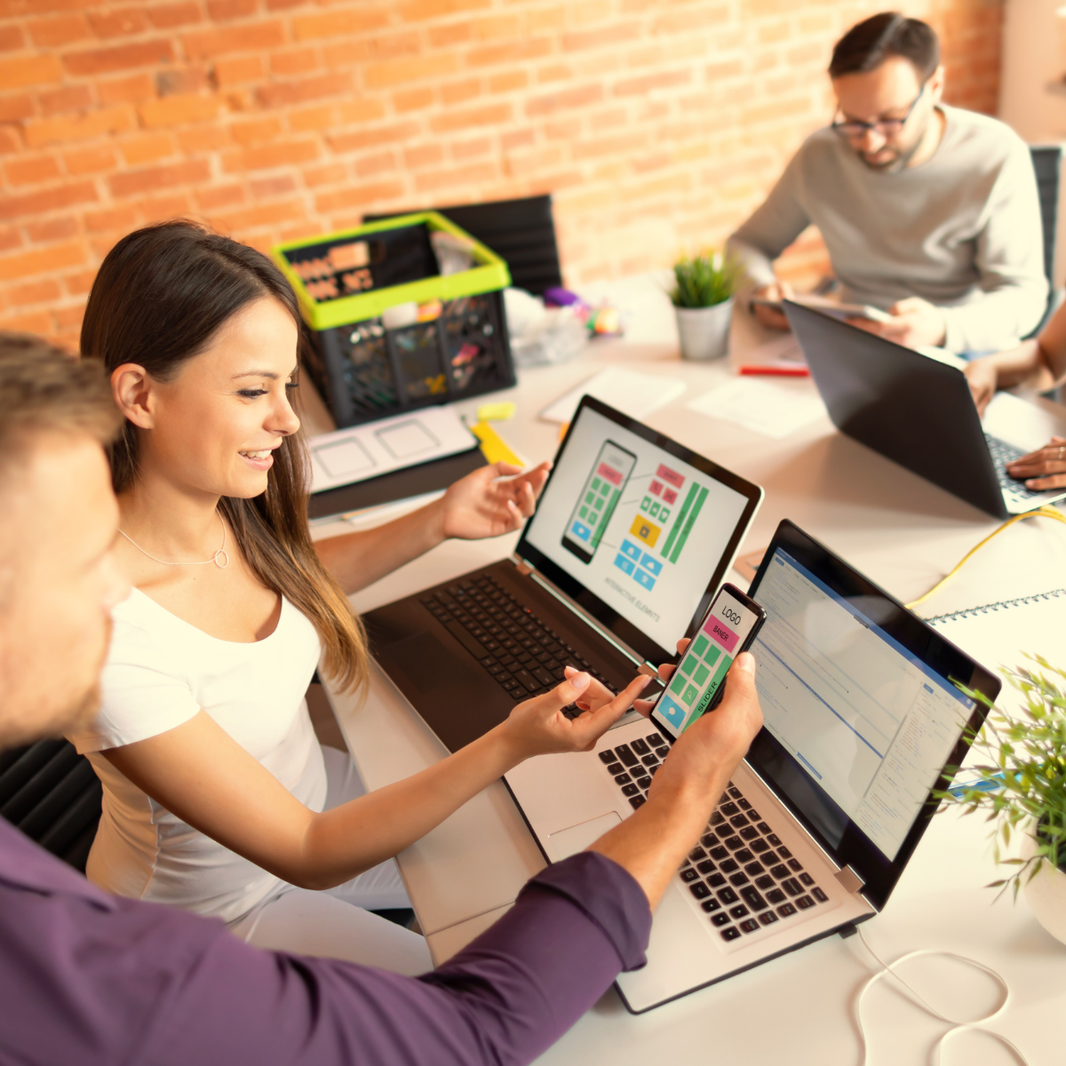 Team testing a mobile UI on laptop and phone